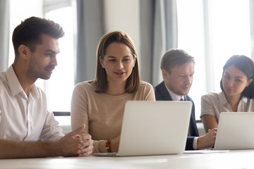 Businesswoman mentor teaching new employee, looking at laptop screen