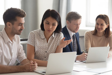 Asian businesswoman mentor teaching male employee, using laptop