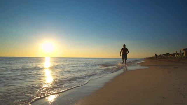 Young active man running on the beach at sunset for healthy lifestyle and wellness
