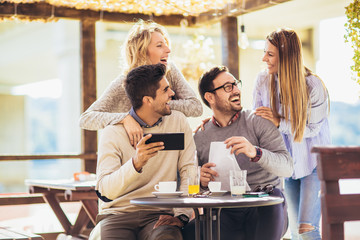 Group of friends in cafe, using digital devices