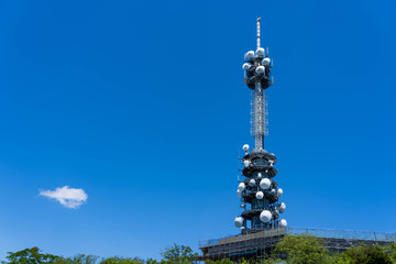 Mast telecommunication TV Antenna Tower wireless satellite in white circle shape on building , television Antenna on blue sky background.