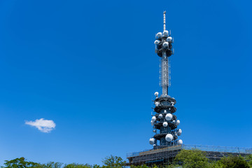 Fototapeta premium Mast telecommunication TV Antenna Tower wireless satellite in white circle shape on building , television Antenna on blue sky background.