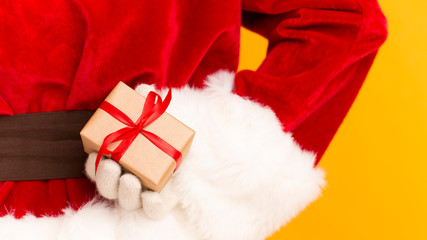 Obraz na płótnie Canvas Santa Claus holding Christmas gift in hand behind his back