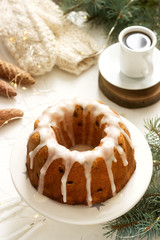 Pie with raisins and icing from powdered sugar on the background of fir branches and garlands. Rustic style.