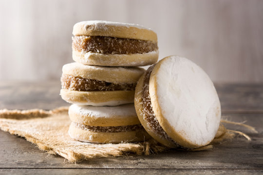 Traditional Argentinian alfajores with dulce de leche and sugar on wooden table