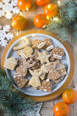 Gingerbread cookies on a concrete tray on a winter background with tangerines, fir branches and a garland.