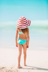 Adorable little girl in big red hat on the beach
