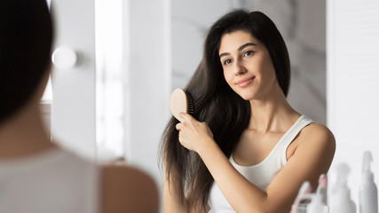 Naklejka premium Girl Brushing Hair Standing In Bathroom, Panorama
