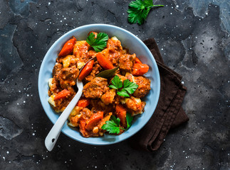 Cozy comfort winter autumn food - spicy braised crock pot beef with potatoes on a dark background, top view