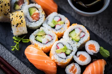 Foto op Plexiglas bovenaanzicht van heerlijke sushi op leisteen bord en eetstokjes © karepa