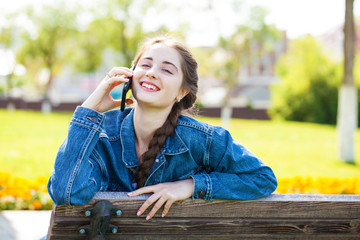 Young girl in jeans jacket calling by phone