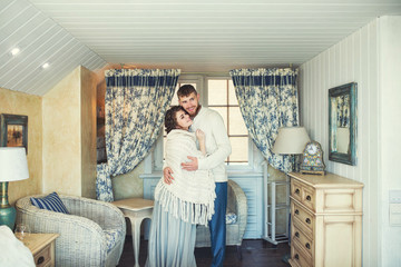 Beautiful and happy young couple man and woman at home in a cozy white interior