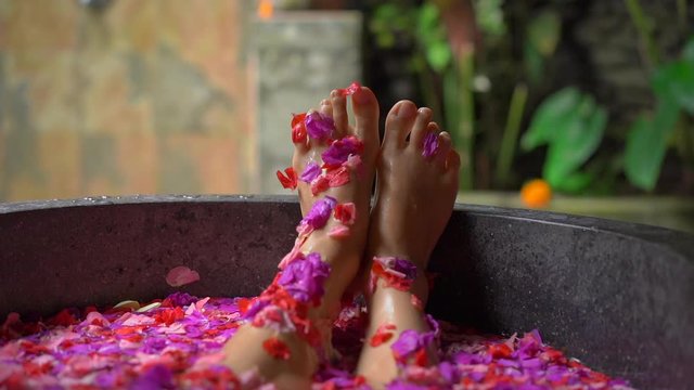 Slowmotion shot of a beautiful young woman taking a floral bath in a tropical spa