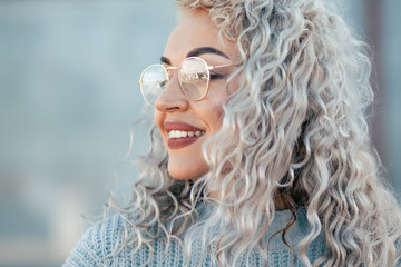 Plus size model with blond curly hair in knitted sweater outdoor