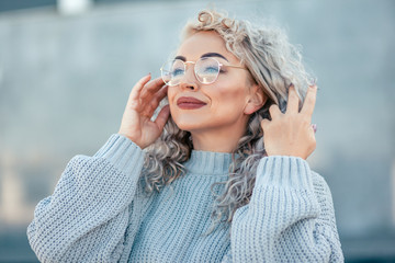 Plus size model with blond curly hair in knitted sweater outdoor
