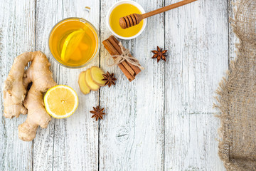 Autumn hot drink tea with ginger, lemon, honey and spices on white wooden background