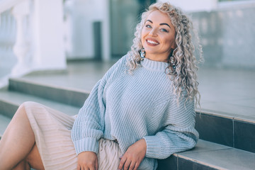 Plus size model with blond curly hair in knitted sweater outdoor