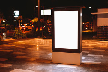 Street advertising mock up template with copy space. Outdoor commercial banner with white empty display on the night street.