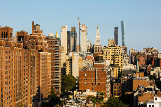 New York City, NY/ USA/ September 28th, 2019: View of tall manhattan towers and skyscrapers rising above brownstones and rooftops