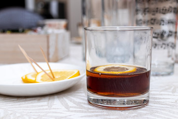 Rum cola casual cocktail with lemon on the white table.