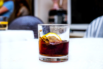 Rum cola casual cocktail with lemon on the white table.