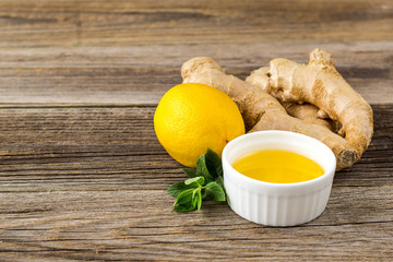 Ginger root lemon mint and honey ingredients for natural hot drink on wooden background