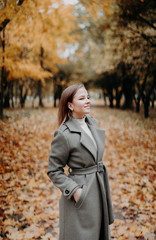 young woman in a long gray-green coat in the autumn forest. large image.