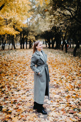 young woman in a long gray-green coat in the autumn forest. large image.