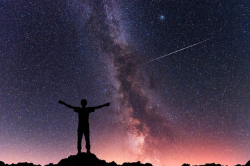 Fototapeta na wymiar Man silhouette standing on the hill. Behind him beautiful milky way galaxy. Night photography.