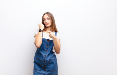 young pretty woman looking impatient and angry, pointing at watch, asking for punctuality, wants to...