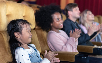 Cute little kids with parent smiling joyfully watching a movie at the cinema entertainment.