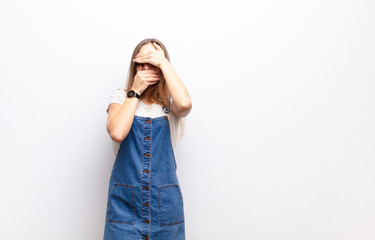 young pretty woman covering face with both hands saying no to the camera! refusing pictures or...
