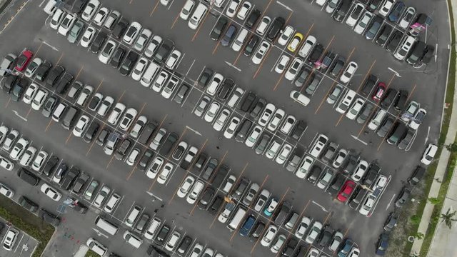 Aerial top down view over outdoor parking lots with full of many vehicles.