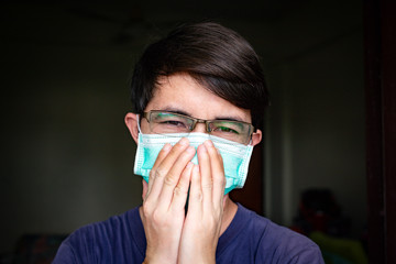 Ill Asian man with eyeglasses wearing hygienic mask, Man with face mask coughing