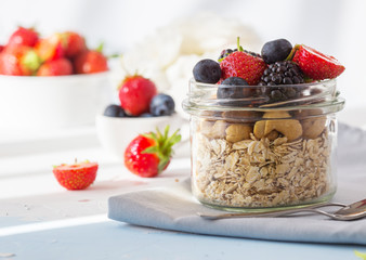 Granola with yogurt and berries for healthy breakfast. Bowl of granola, almonds, blueberries and strawberries, top view, copy space.