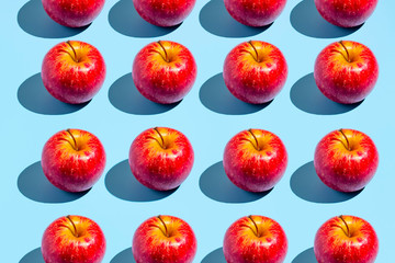 Colorful fruit pattern of fresh red apples on blue background. From top view. Creative concept.