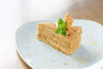 Honey sponge cake decorated with meringue and mint leaves. Breakfast in the cafe, morning coffee. on wooden table. Restaurant menu