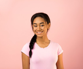 Joyful girl in pink t-shirt smiling to camera, pink background