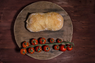 Top view of italian ciabatta bread with cherry tomatoes on wooden board