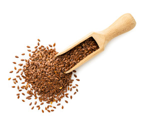 Flax seeds in a wooden scoop on a white background. The view of the top.