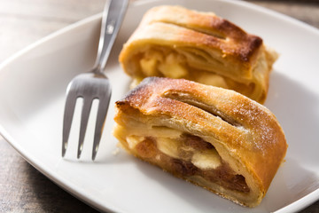 Traditional homemade apple strudel slice on wooden table