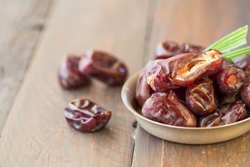 Dates on plate on wooden background, top view, copy space. Organic dried dates fruits.