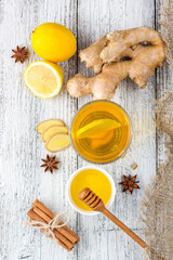 Fototapeta na wymiar Autumn hot drink tea with ginger, lemon, honey and spices on white wooden background
