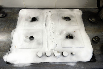 cleaning agent foam on a gas stove. cleaning the kitchen.