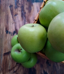 green apples in a basket on  wooden table closeup