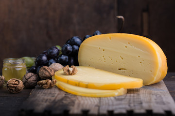 Dutch hard cheese Maasdam or Emmentaler, with honey fruit and grape