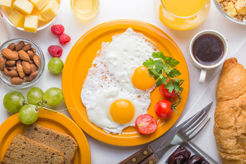 Homemade breakfast with sunny side up fried egg croissant toast coffee fruits vegetable and orange juice in top view with copy space. Delicious homemade american breakfast concept for background. Amer