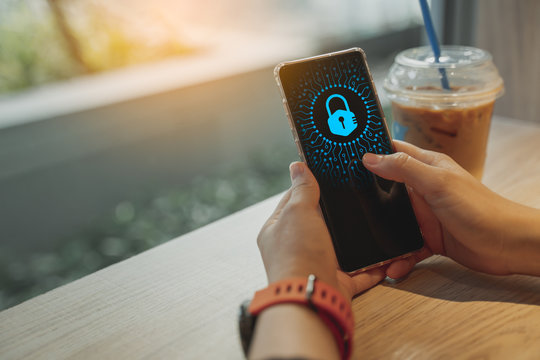 Cyber security and data protection concept, woman using smartphone and lock icon on virtual screen.female hand holding touch phone with lock icon on screen above the table in cafe.