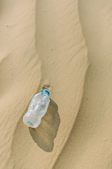 Fototapeta na wymiar Plastic bottle of water abandoned in the sand.
