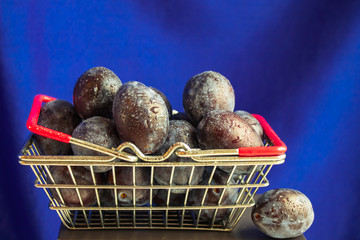 Basket of ripe plum fruits close up on a blue background
